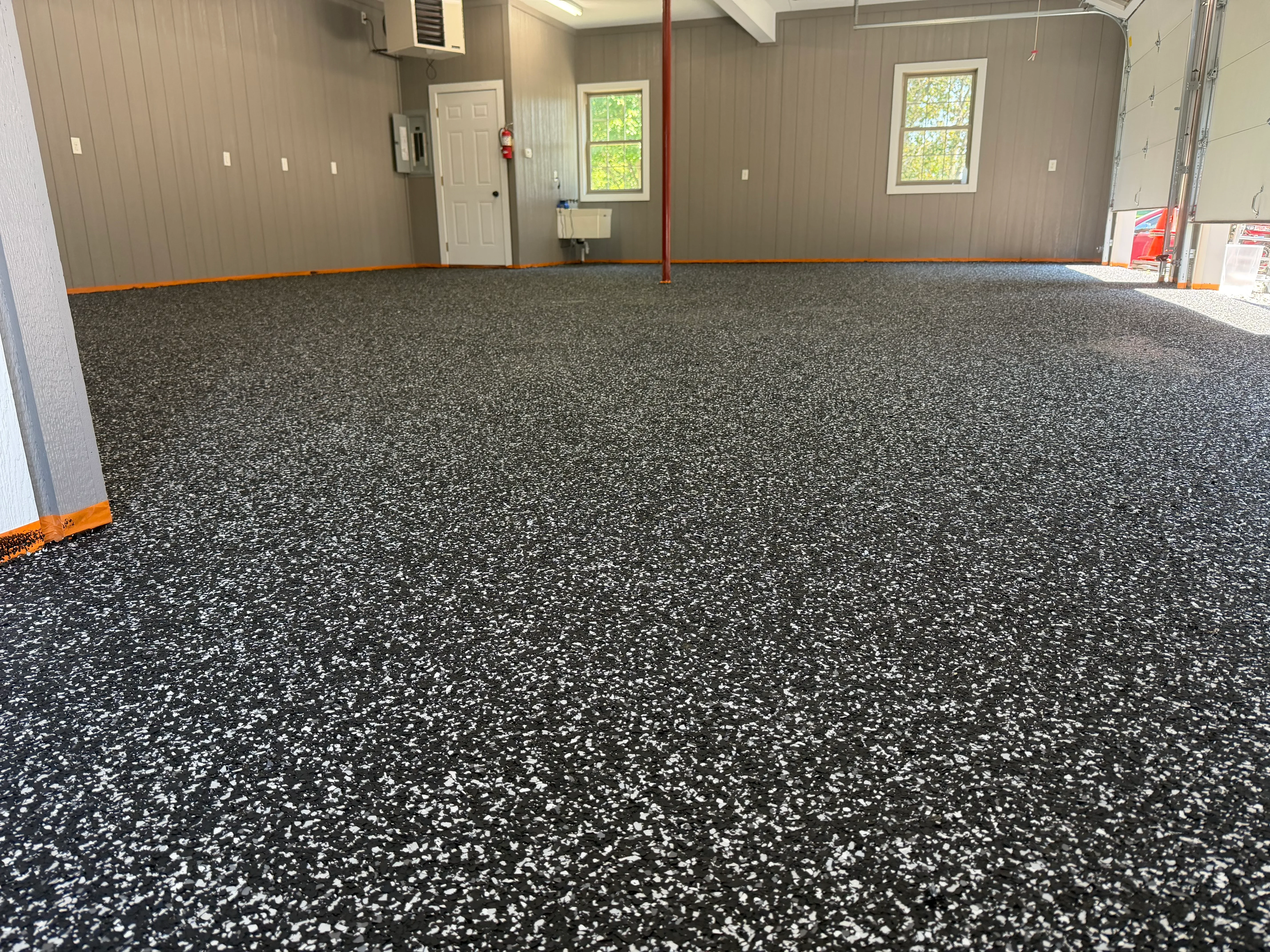 Charcoal gray epoxy garage floor with white speckle aggregate, seamless finish in large industrial space