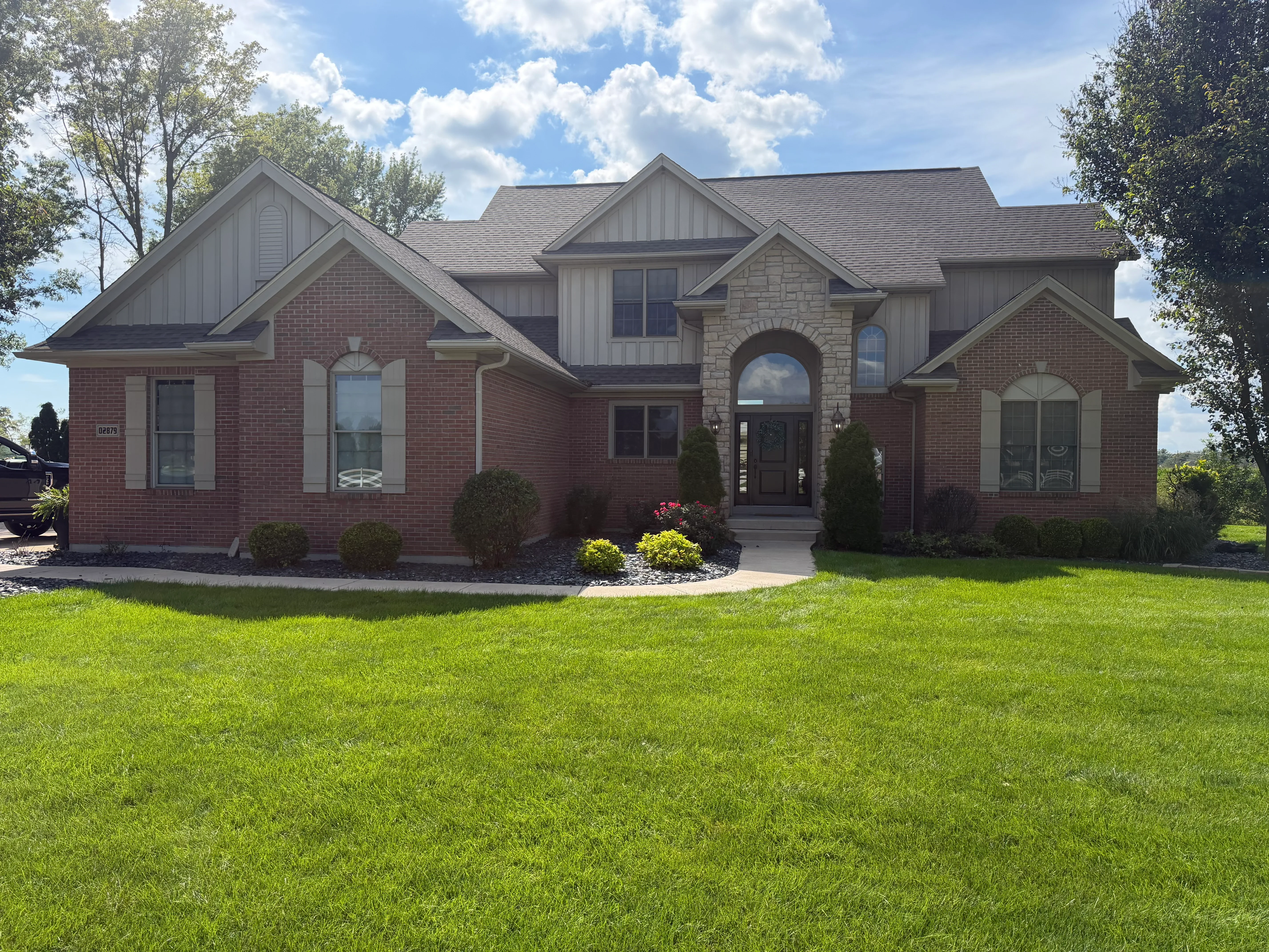 Red brick and stone two-story home with gray painted trim and siding
