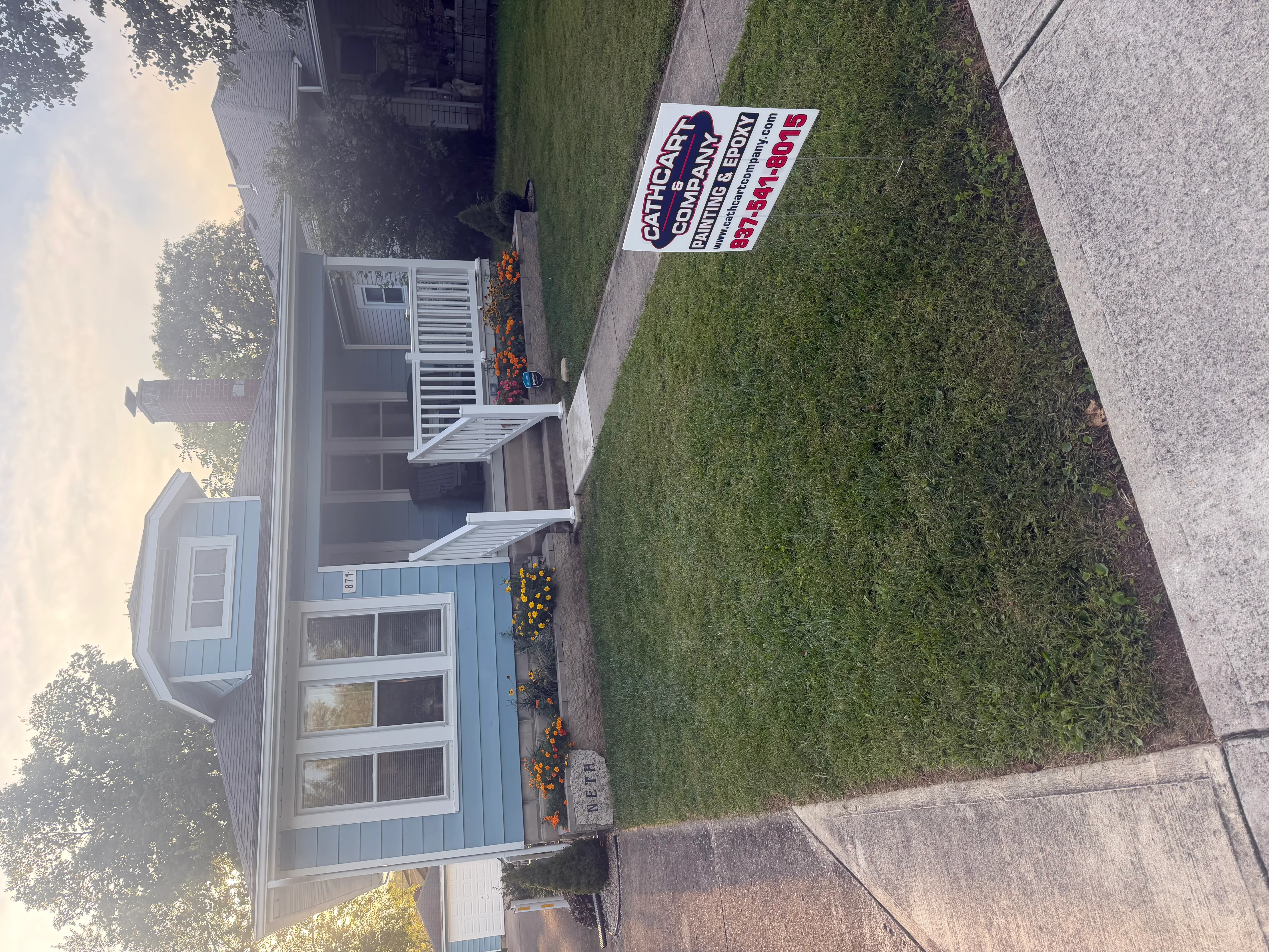 Blue metal siding house with white trim and window frames, freshly painted exterior